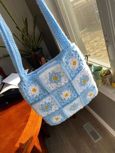 a crocheted bag hanging from a window sill next to a potted plant