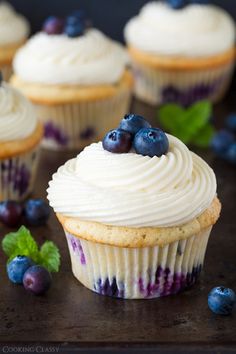 blueberry cupcakes with white frosting and fresh berries on the side, ready to be eaten