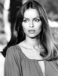 an old black and white photo of a woman with long hair wearing a blouse, looking at the camera