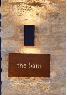 the barn sign is lit up in front of a stone wall with a light on it