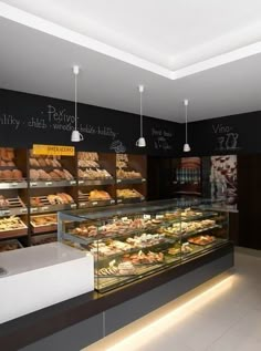 a bakery filled with lots of pastries on display in front of a chalkboard wall