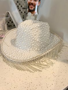 The perfect hat to hit the town running on your bachelorette. This hand made cowboy hat is covered in white pearls and finished with a fringe. Don't miss out on this beautiful custom hat! Diy Bedazzled Cowboy Hat, White Fedora Mini Hat For Party, White Beaded Curved Brim Hat, White Beaded Hats For Festival, White Beaded Hat With Short Brim, White Beaded Short Brim Hat, Bridal Cowboy Hat, Bedazzled Cowboy Hat, Rodeo Barbie