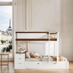 a white bunk bed sitting in a bedroom next to a window with a view of the eiffel tower