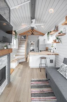 the interior of a tiny home with wood floors and white walls, gray couches