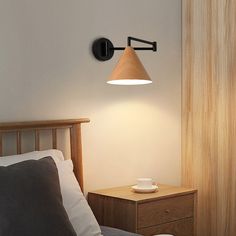 a bedroom with a lamp on the wall next to a night stand and bed in it