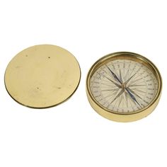 an old brass compass is next to a round metal object on a white background with clippings