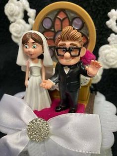 a wedding cake topper with a bride and groom sitting on a chair in front of a stained glass window