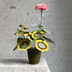 a potted plant sitting on top of a table with paper cut out flowers in it