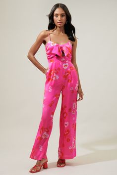 Add the sweetest pop of pink to your wardrobe in the Cherry Blossom Raleigh Jumpsuit. Sleek satin covered in pink tonal sakura blossoms decorate a straight leg jumpsuit. It features a bow tie detail at the chest that sits atop a little cut out. - Lined- Cut out- Pockets- Zipper- Color: Pink Red MultiSize + Fit - Model is 5'10" and wearing size XS- Measurements taken from size S - Waist: 14 1/2"- Inseam: 30 3/4" Fabric Self: 100% Polyester, Lining: 97% Polyester, 3% Spandex Style Number STP7360P Spring Satin Fitted Jumpsuits And Rompers, Spring Party Satin Jumpsuits And Rompers, Satin Jumpsuits And Rompers For Spring Party, Fitted Satin Jumpsuits And Rompers For Spring, Fitted Pink Jumpsuits And Rompers, Pink Party Jumpsuits And Rompers, Chic Pink Floral Print Jumpsuit, Chic Pink Floral Print Jumpsuits And Rompers, Feminine Sleeveless Jumpsuits For Spring