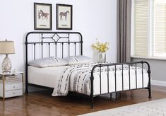 a bedroom with a metal bed frame and white linens on the floor, along with two framed pictures