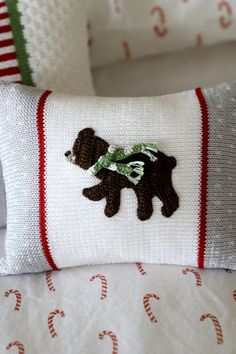 a pillow with a bear on it sitting on a bed next to candy canes