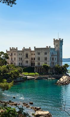 an old castle sitting on top of a cliff next to the ocean with blue water