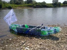 a boat made out of plastic bottles is sitting on the shore with a flag in it