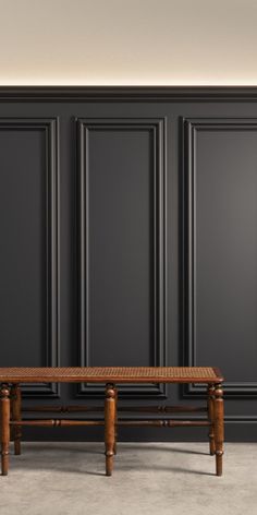 a wooden bench sitting in front of black paneled walls