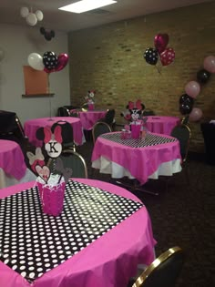 a minnie mouse themed birthday party with pink and black tablecloths, polka dot centerpieces and balloons