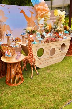 a baby giraffe standing in front of a table filled with cakes and desserts