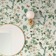 there is a mirror on the wall next to a flowered wallpaper with butterflies