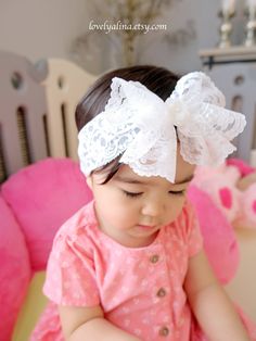 A beautiful lace bow headband suitable for all ages! Bow is approximately 5" wide attached to a 2" wide stretch lace. Offering different kinds of gem at the center of the bow to create a a diverse look.  Currently, photos are showing gem #1 and #2.  ⭐️Please note, gem sizes are different, therefore the result of the overall bow look may be slightly different than in photos. Also, due to the nature of this bow type, the shape/drape may slightly vary as well. Bow may look bigger in photos due to t White Bow Headband For Wedding, White Satin Bow Headband, White Wedding Headband With Bow, Adjustable White Lace Hair Accessories, Cute White Headband With Pink Bow, White Matching Headband For Baptism, White Hair Accessories With Matching Headband For Baptism, Cute Adjustable Headband For Wedding, Cute Adjustable Headband For Weddings