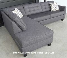 a gray sectional couch with two pillows on it