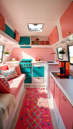 the interior of a camper with pink and turquoise accents on the walls, rugs, and cabinets