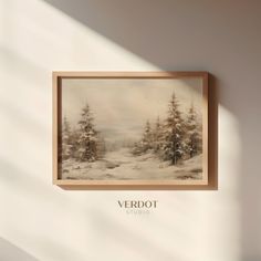 a painting hanging on the wall in front of a white wall with trees and snow