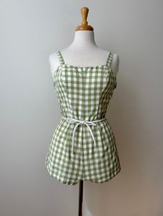 The most adorable green and white gingham play suit from the 1950's.  This cotton cutie features smocked sides for stretch, a waist tie belt and is fully lined in cotton. Fastens up the centre back with a metal zipper and has a fabric backing so the zipper doesn't actually touch your skin.  The straps have adjustable length settings with button fastening and there's the sweetest scalloped trim along the bust.  In excellent condition with the only flaw to note being a faint stain one one side in Vintage Cotton Jumpsuits And Rompers, Spring Fitted Gingham Jumpsuits And Rompers, Fitted Gingham Jumpsuits And Rompers For Spring, Summer Gingham Cotton Jumpsuits And Rompers, Vintage Green Cotton Jumpsuits And Rompers, Vintage Green Jumpsuits And Rompers For Summer, Vintage Playsuit, Play Suit, Vintage Romper