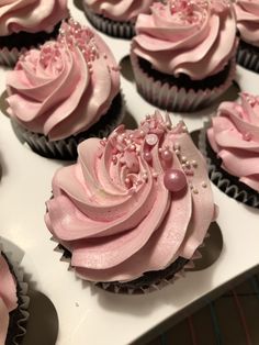 cupcakes with pink frosting and pearls on them are arranged in a box