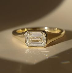 an engagement ring with a baguette cut diamond in the center on a white surface