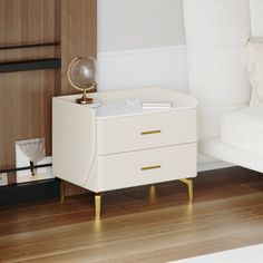 a white bed sitting next to a night stand on top of a hard wood floor