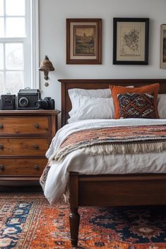 a bedroom with a bed, dresser and pictures on the wall