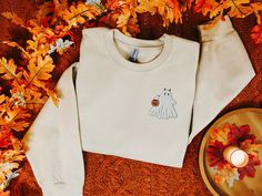 Halloween Embroidered Sweatshirt, Embroidered Ghost Sweatshirt, Cute Boo Ghost Crewneck Sweater, Boo Sweatshirt, Fall Clothes, Fall Apparel Embrace the mischievous side of Halloween with our cozy sweatshirt featuring an embroidered ghost with devil horns, holding a jack-o'-lantern bucket. This playful design perfectly captures the spooky and fun spirit of the season, adding a unique twist to your Halloween wardrobe. Made from soft, high-quality fabric, this sweatshirt ensures warmth and comfort White Embroidered T-shirt For Fall, White T-shirt With Custom Embroidery For Fall, Custom Embroidered White T-shirt For Fall, White Custom Embroidered T-shirt For Fall, White Embroidered Logo T-shirt For Fall, Halloween White Sweatshirt With Embroidered Graphics, White Halloween Sweatshirt With Embroidered Graphics, White Custom Embroidered Top For Halloween, White T-shirt With Embroidered Graphics For Fall