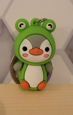 a green and white animal shaped keychain sitting on top of a wooden table