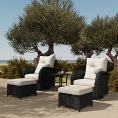 two chairs and a table sitting on top of a stone floor next to an olive tree