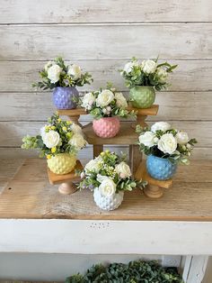 there are many small vases with flowers in them on top of a table next to each other