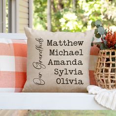 a pillow sitting on top of a white bench next to a basket filled with flowers