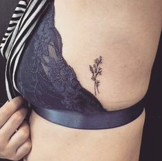 a woman's stomach with a small flower tattoo on the side of her belly