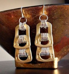 two pairs of earrings sitting on top of a wooden table next to a metal object