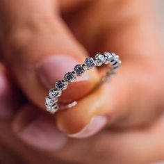 a woman's hand holding a diamond ring in the middle of her fingers,