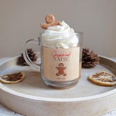 a cup with whipped cream in it on a tray next to orange slices and pine cones