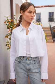 An oversized fit with classic shirting details in a true cropped length. Designed to wear with all your favorite high waisted denim, trousers & skirts. Shown here in our signature Poplin, this is the wardrobe essential we needed. Pair with the Slouchy High Waisted Trouser for a timelessly chic look. Made in the USA97% Cotton 3% SpandexModel is 5'9.5" and wearing a size 1 Cropped Shirt Outfits Women, How To Style White Crop Top, Crop Shirt Styling, Cropped Button Down Outfit, Cropped White Blouse Outfit, Oversized Crop Shirt, Cropped Poplin Shirt Outfit, Cropped Shirt Women, Cropped White Button Down Shirt Outfit