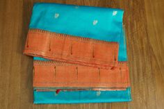 two orange and blue sarees on a wooden table