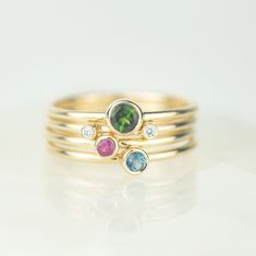 Introducing the Draco solid gold stacking ring set. The collection features vibrant jewel toned gems and sparkling diamonds set in solid recycled 9ct gold. Two tiny diamonds sit on one band, slightly apart, designed to sit beautifully on either side of the green tourmaline, ruby and london blue topaz rings. Our Andromeda stacking ring sets are named after constellations - Draco being the dragon. The rings are designed to be worn together and apart, creating a beautifully varied set. Material - M Yellow Gold May Birthstone Ring With Gemstone Accents, Diamond Stackable Rings For May Birthstone, Diamond Stackable Rings With May Birthstone, Yellow Gold Diamond Stackable Birthstone Rings, Stackable Yellow Gold Jewelry With Blue Topaz, Yellow Gold Topaz And Diamond Birthstone Ring, Yellow Gold Stackable Rings With Gemstone Accents, Yellow Gold Diamond Ring With Blue Topaz Birthstone, Fine Jewelry Diamond Stackable Topaz Ring