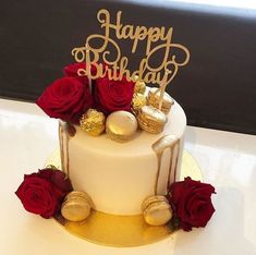 a white cake with red roses and gold decorations