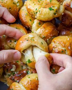 two hands picking up some bread rolls with cheese and parmesan sprinkles