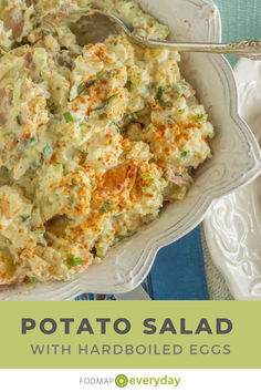 potato salad with hard boiled eggs in a white bowl on a blue and white plate