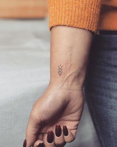 a woman's hand with a small arrow tattoo on it