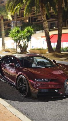 a red bugatti is parked on the side of the road in front of some palm trees