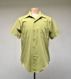 * Men's casual shirt c 1970s* Green polyester-cotton blend fabric * Medium pointed collar* Double chest patch pockets * Short, set-in sleeves with sewn down notched cuff with button detail* Action pleats below back yoke* 6 button front closure* Long tailsLabel: Master Built - Permanent Press - 15 1/2Excellent conditionChest: 44Shoulder: 18Sleeve: 9Length: 31 (center back)Garments are flat-measured. Please compare these measurements to another flat-measured garment that fits you correctly for siz Retro Cotton Camp Shirt For Spring, Retro Green Collared Shirt, Spring Retro Cotton Camp Shirt, Retro Cotton Collared Camp Shirt, Retro Green Cotton Shirt, Green Retro Cotton Shirt, Retro Cotton Tops With Pockets, Retro Shirt With Johnny Collar And Relaxed Fit, Retro Shirt With Pockets In Relaxed Fit