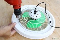 a person is using a drill to fix a fan