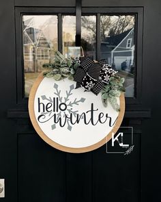 a black and white door with a wreath on it that says hello winter in the center